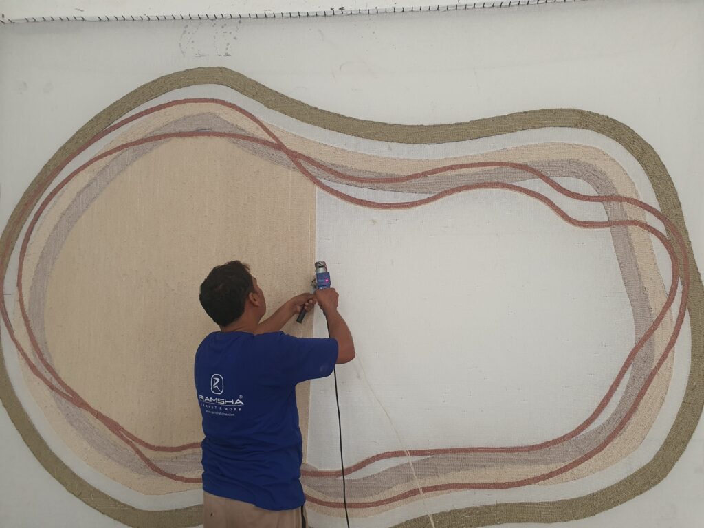 Skilled artisan hand-tufting a custom-designed carpet with precision and care at Ramsha Carpets