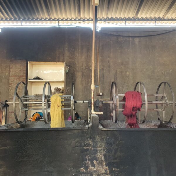 Skilled technician dyeing wool fibers in vibrant colors for high-quality carpet production at Ramsha Carpets