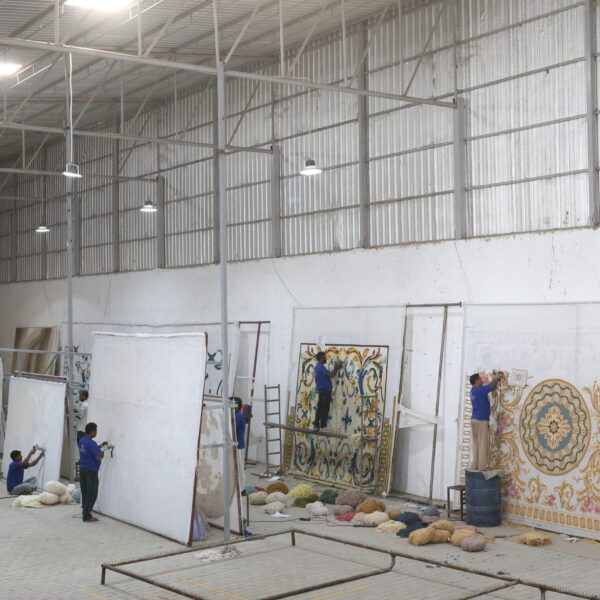 Skilled artisan hand-tufting a custom-designed carpet with precision and care at Ramsha Carpets