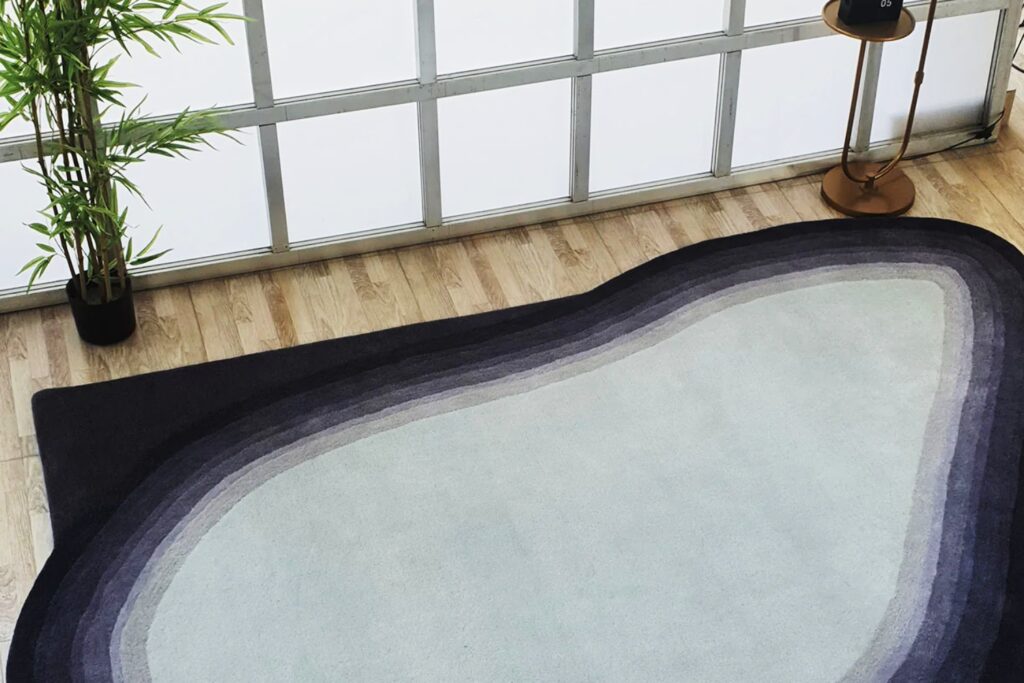 A sophisticated living room featuring luxury Handmade Rugs from Ramsha Carpets under a modern curved sofa.