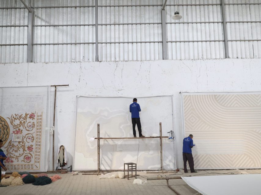 Skilled artisan hand-tufting a custom-designed carpet with precision and care at Ramsha Carpets